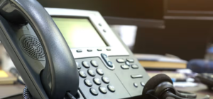 Desk phone with handset and headset in an office setting, representing professional call handling and customer support.