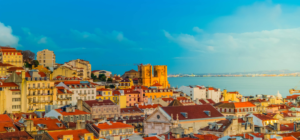 View of Lisbon’s Alfama district with colourful rooftops and historic buildings overlooking the Tagus River.